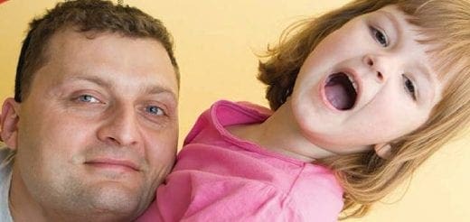 Man holding a distressed child with mouth open.