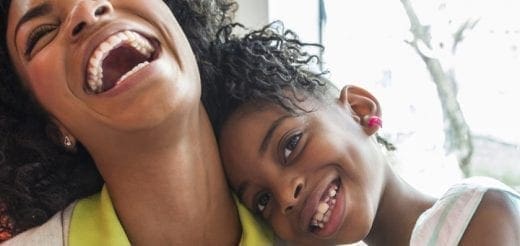 Two smiling women, one with mouth open in laughter.