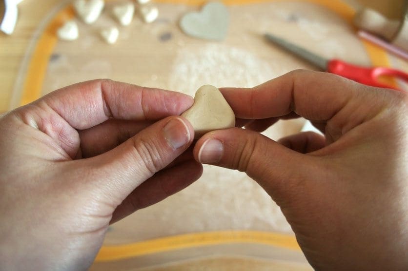 Hands shaping a heart from air-dry clay.