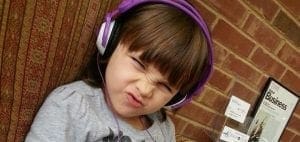 Child with purple headphones making a funny face.