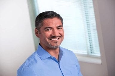 Pedro-Leon, a man with short, dark hair and a goatee, smiles in a blue collared shirt.