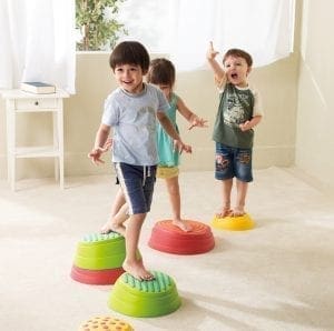 Three children play on colorful stepping stones.