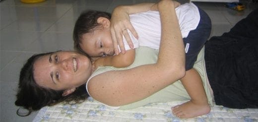 Woman lying on her back with a baby on top of her.