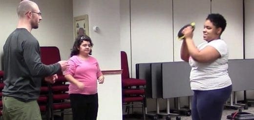 Three people in a room, two women and one man, are engaged in a fitness activity.
