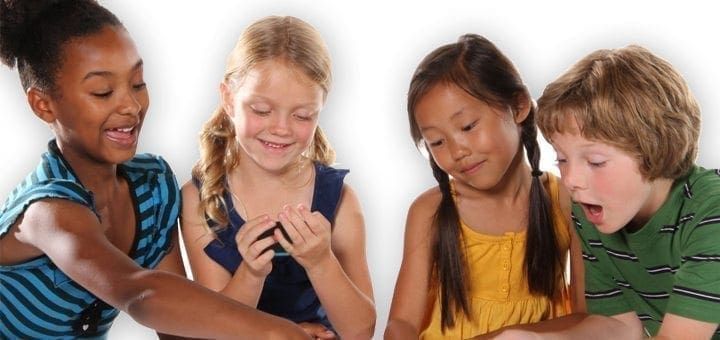 Four children gather around a table, looking at something small in their hands.