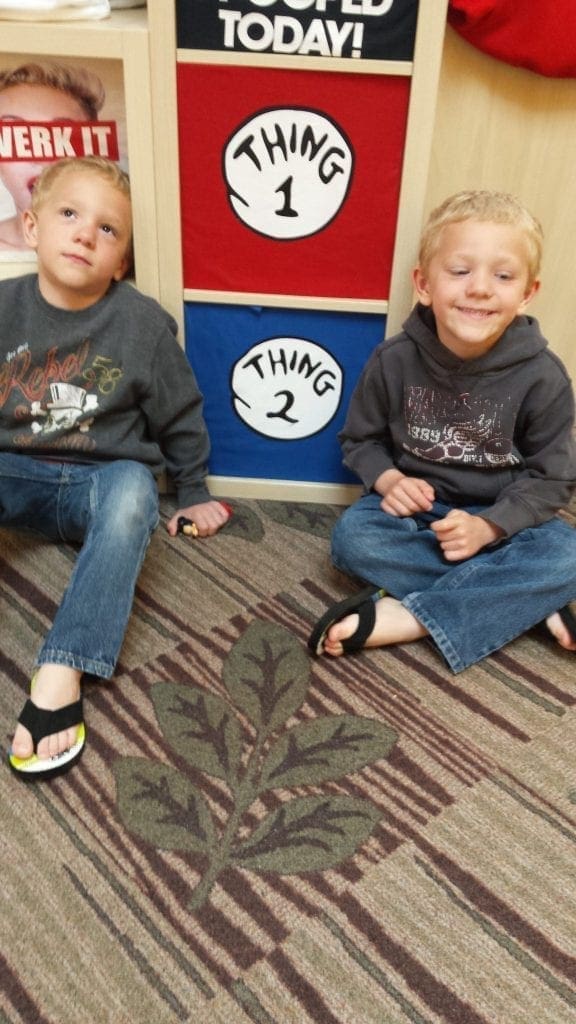 Hampen and Harrisen sit on the floor in front of a Thing 1 and Thing 2 decoration.
