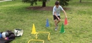 Young person navigating cones and hurdles on grass