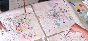 Children painting with eyedroppers and blowing paint on paper.