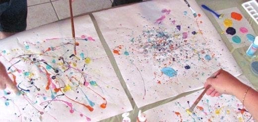 Children painting with eyedroppers and blowing paint on paper.