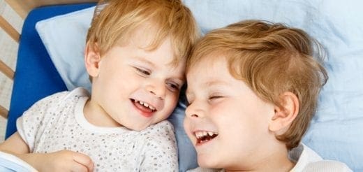 Two young boys with blonde hair laughing together.