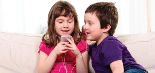 Two children listen to a phone with headphones.