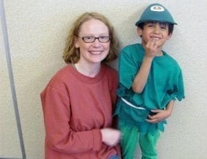 A woman and a young boy wearing a costume and hat smile at the camera.