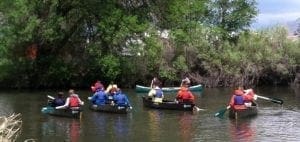 Group of people canoeing on a river surrounded by trees