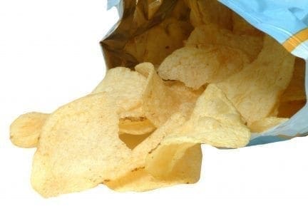 Potato chips spilling out of a bag against a white background.
