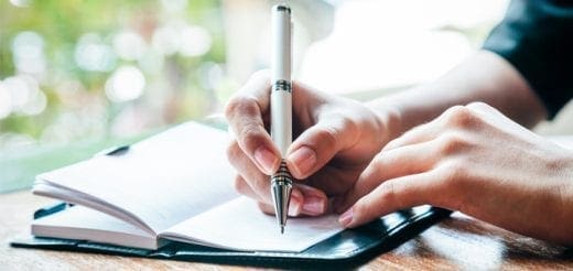Hands writing in a journal with a pen