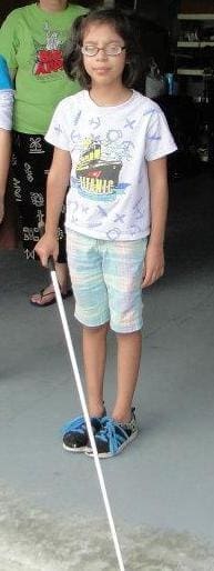 Torrie holding a white mobility cane.