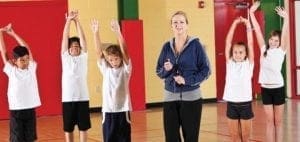 Physical education class with instructor and students exercising