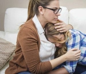 Woman comforting a distressed teen.