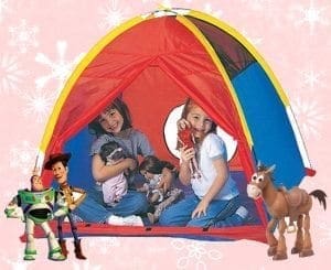 Toy Story characters Buzz Lightyear and Woody stand outside a colorful play tent where two children are playing with dolls.