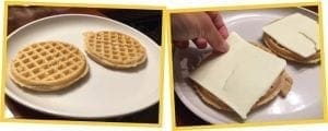 Two waffles are on a plate, and a hand places cheese on top of a waffle sandwich.