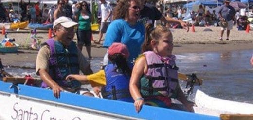 People in a boat wearing life jackets at a beach event