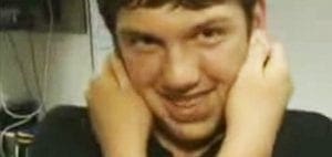 Young man with hands on his head smiling.