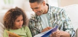 A father and daughter read a book together.