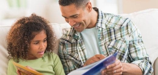 A father and daughter read a book together.
