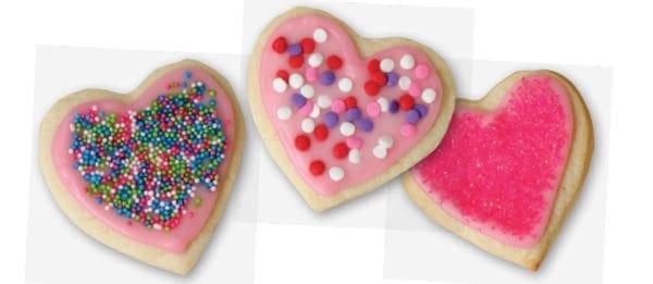 Three heart-shaped cookies decorated with pink frosting and sprinkles.