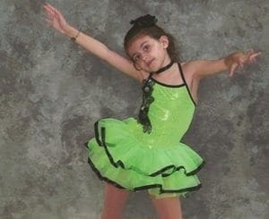 Young girl in a lime green dance costume with her arms outstretched.