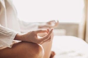 Person in a white shirt meditating with hands in lap.