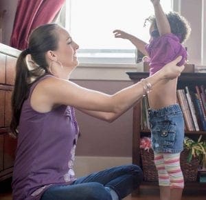Woman helping a child put on a shirt.
