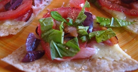 Rice tortilla pizzas topped with tomatoes, olives, and greens.