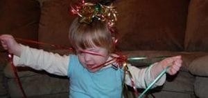 Child tangled in colorful ribbons and bow