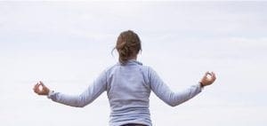 Woman meditating with arms outstretched and hands in mudra pose.
