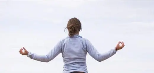 Woman meditating with arms outstretched and hands in mudra pose.