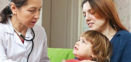 Doctor with stethoscope talks to a mother and child.