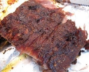 Rack of ribs coated in a dark spice rub.