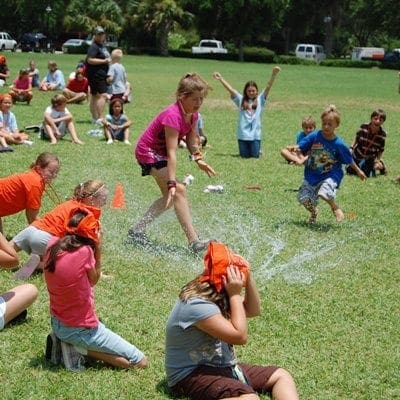 Children playing a water game on a grassy field.