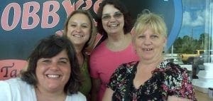 Four women smiling in front of a sign that says "BOBBY'S".