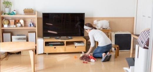Woman picking up toys from the floor in a living room.