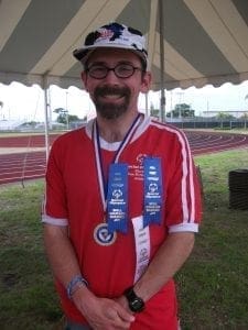 Michael wearing a red shirt with medals and ribbons, and a cow-patterned hat.