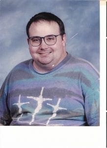Mike smiling in a colorful striped t-shirt with figures.