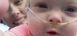 A child with nasal cannulas smiles next to a woman.