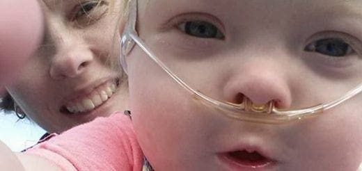 A child with nasal cannulas smiles next to a woman.