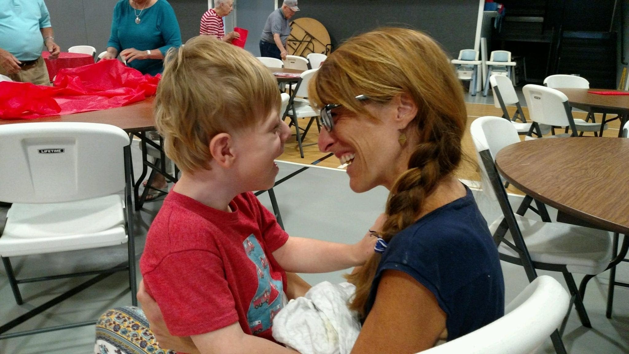 A child and an adult smile at each other, sitting at tables.