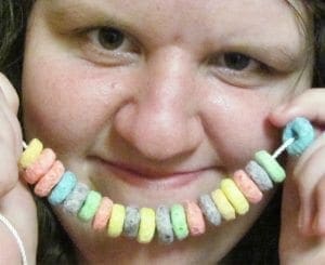 Child holding a necklace made of colorful cereal loops.