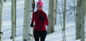 Woman running through a snowy forest.