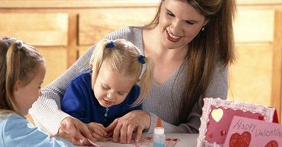 Woman and two children crafting a Valentine's Day card.