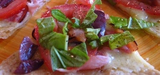 Mini pizzas with tomatoes, olives, and basil on a tortilla base.
